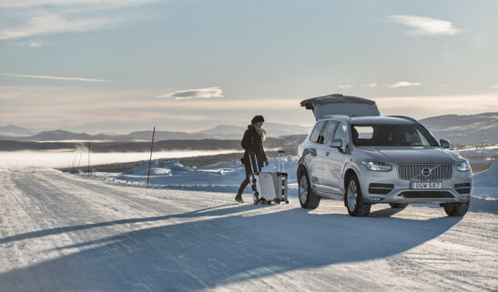 Girl loading Volvo car in the road. The setting is in northern Sweden in the sunset.